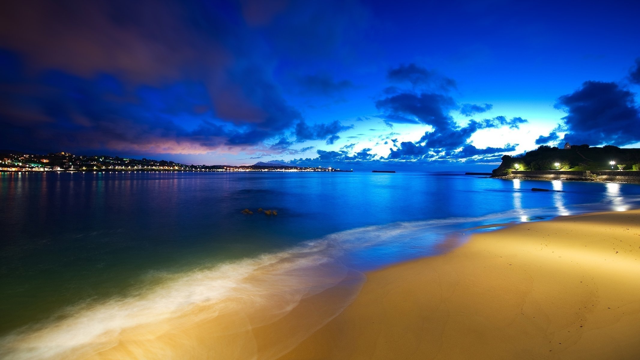 the ocean clouds the sky lights the evening beach