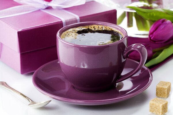 Coffee in a purple cup with a spoon and sugar