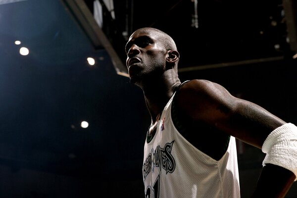 Dark-skinned basketball player on a dark background with lights