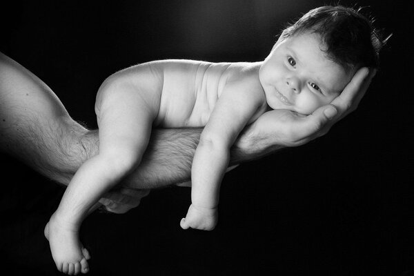 Le bébé est couché sur la main de papa