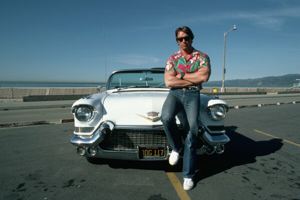 Młody Terminator pozuje na tle białego Cadillaca