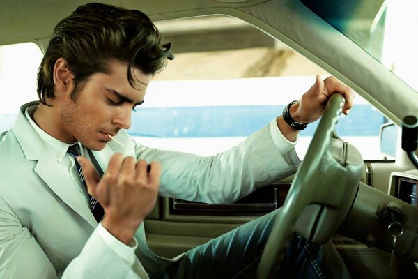 A young man is sitting in a car and smoking