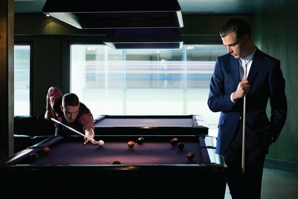 Men in suits play billiards