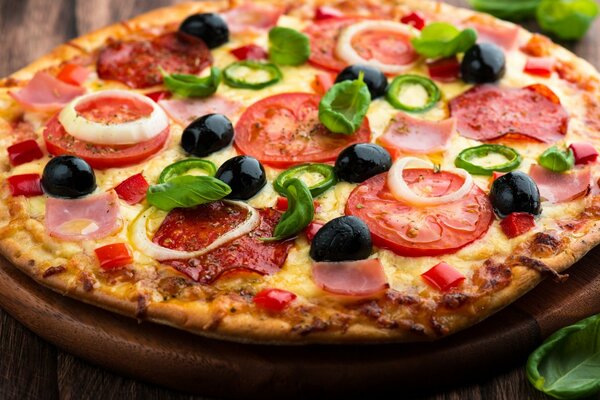 Pizza su una tavola con pomodoro, formaggio, olive e cipolle