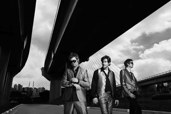 Three men are standing under the bridge