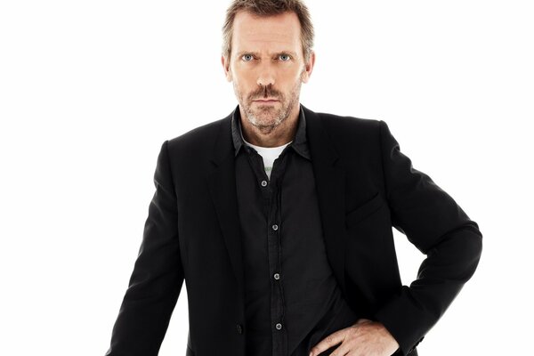 Dr. House stands in a pose with his hand on his waist