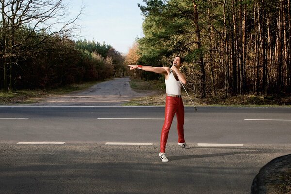 Freddie Mercury sings on the road. Forest in the background