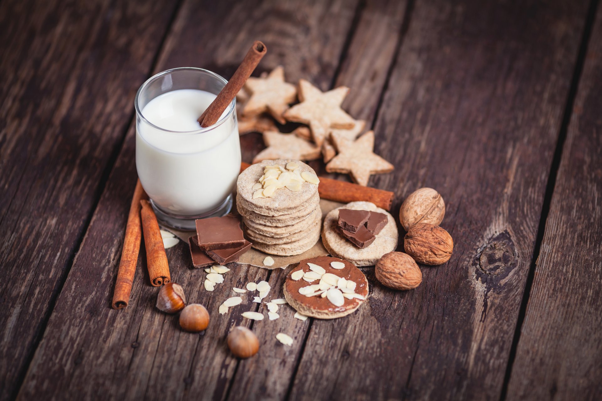 glas milch zimt stäbchen nüsse haselnüsse walnüsse mandeln kekse schokolade bretter