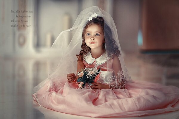 A little girl in a bride s outfit. A child with a bouquet