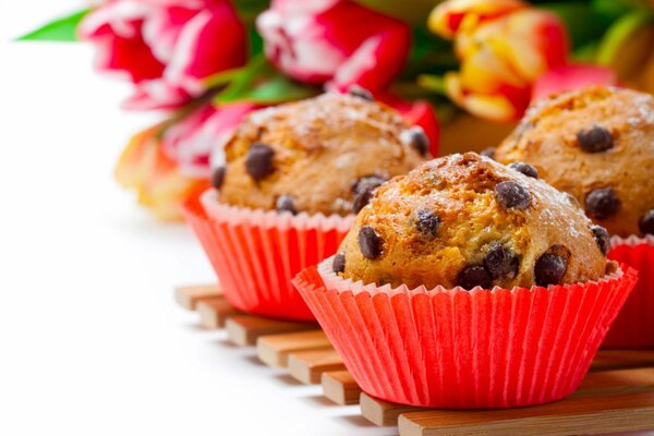 Cupcakes con cioccolato su sfondo di un mazzo di fiori