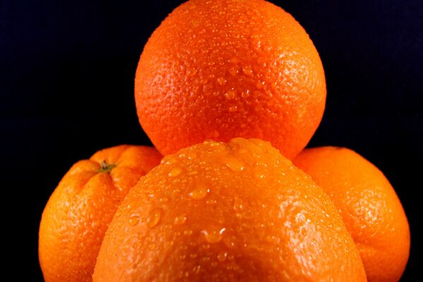 Gotas de agua sobre naranjas sobre fondo negro