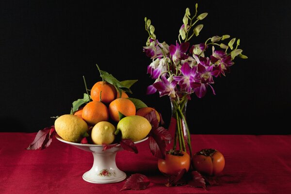 Florero con frutas y flores de pie cerca