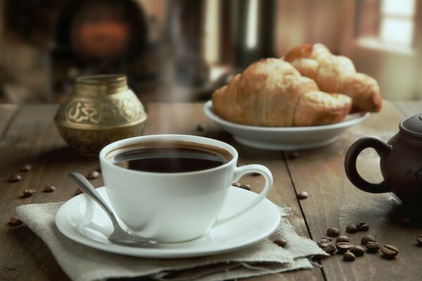 Stillleben. Becher mit Untertasse. Croissants auf einem Teller