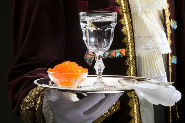 A glass of vodka with caviar on a tray