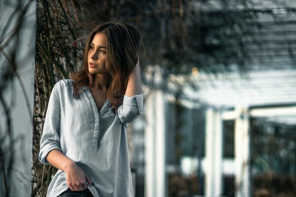 A pretty woman in a blouse stands thinking