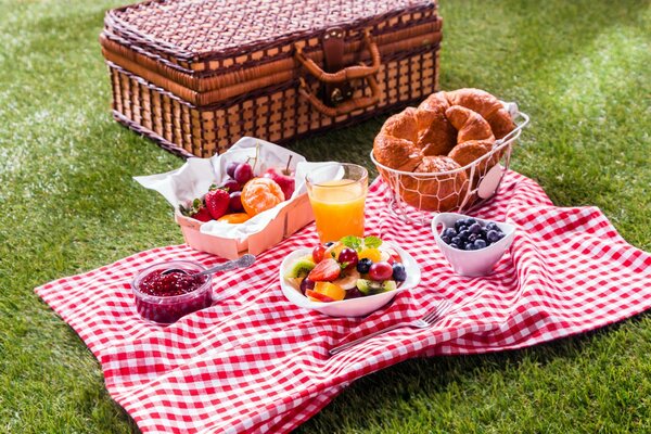 Picnic in the clearing. Croissants, fruit, juice wicker chest