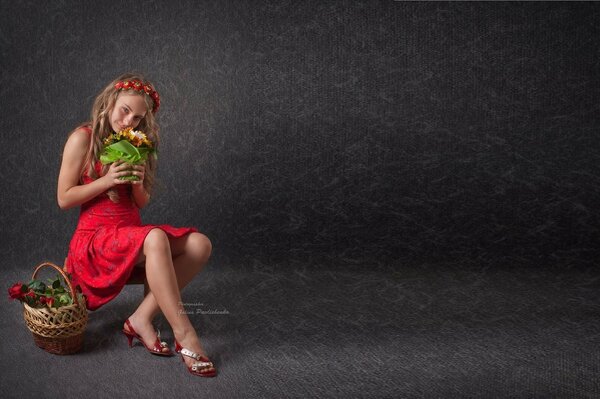 A girl is sitting in a dress with a basket of fruit