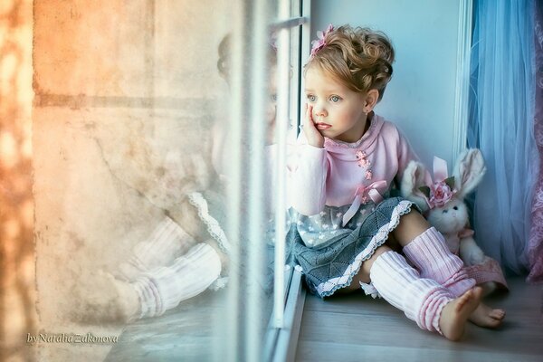 Cute girl on the window with a touching toy