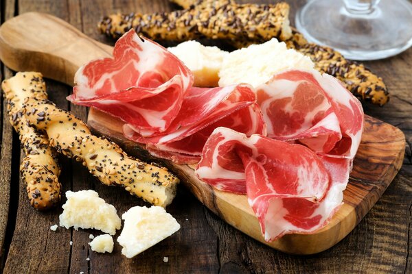 A plate with sliced meat, cheese and baguette