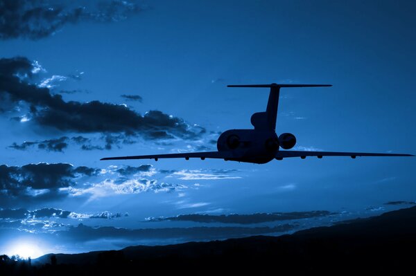 The plane flies through the night sky towards sunset