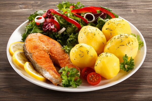 Salmon steak with baked potatoes and salad on a platter