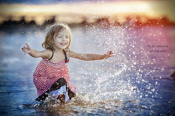 Mała dziewczynka bawi się w wodzie. Zachód słońca na brzegu