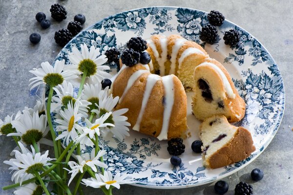 A plate with berry cupcake and flowers