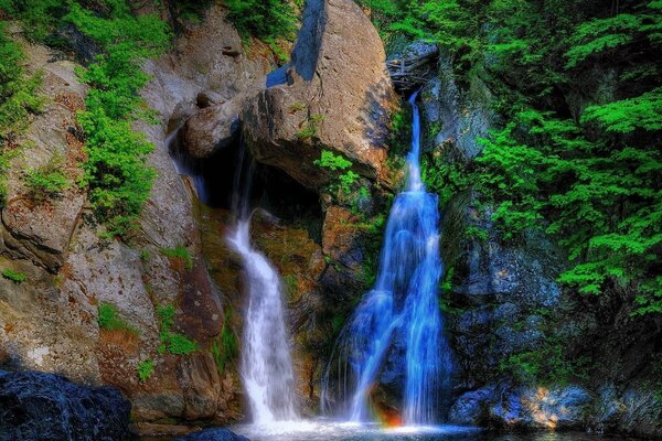 Blaue und weiße Wasserfälle auf dem Hintergrund von Bergen und Wäldern