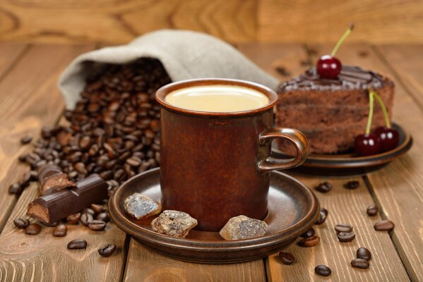 Granos de café, café y pastel de chocolate sobre un fondo de madera