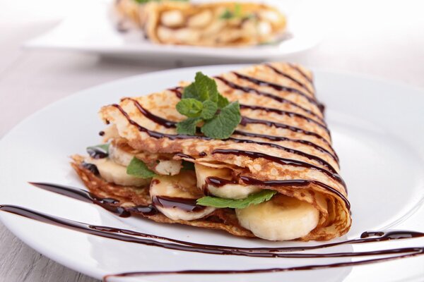 Pfannkuchen mit Banane und Schokolade, garniert mit einem Minzblatt zum Nachtisch