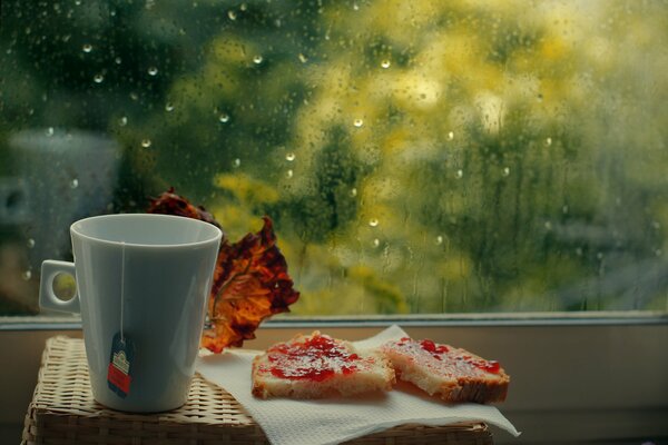 A cup of tea with sweet sandwiches by the window