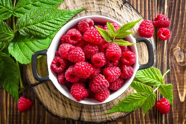 Beautiful photo of raspberry berries with leaves on a wooden backing