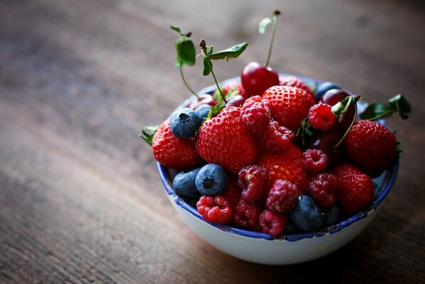 A plate with strawberries, raspberries and blueberries on the table