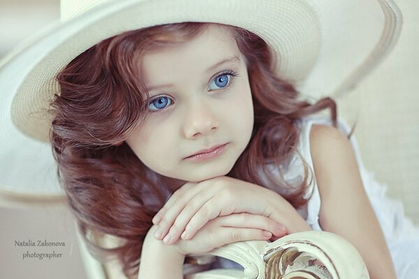 A beautiful girl with blue eyes. The child in the hat