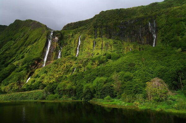 Krajobraz przedstawiający zielone góry i wodospady
