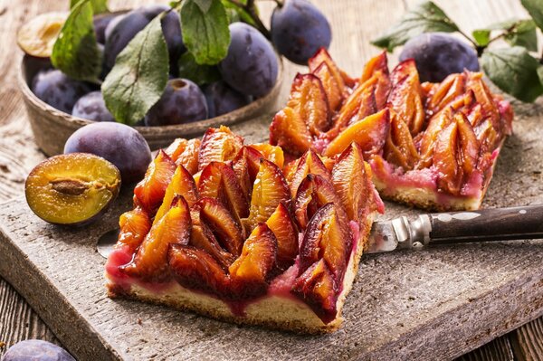 Delicious, beautiful plum pie on a wooden board with fresh plums next to it