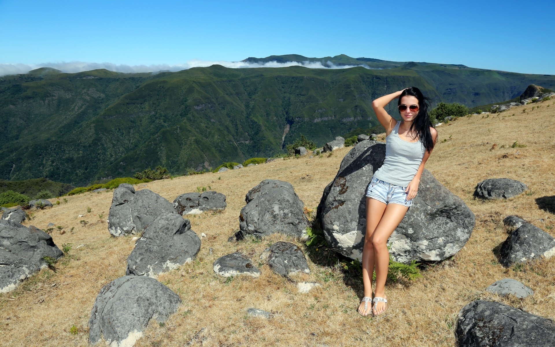 ragazza bruna gambe posa montagne pietre cielo