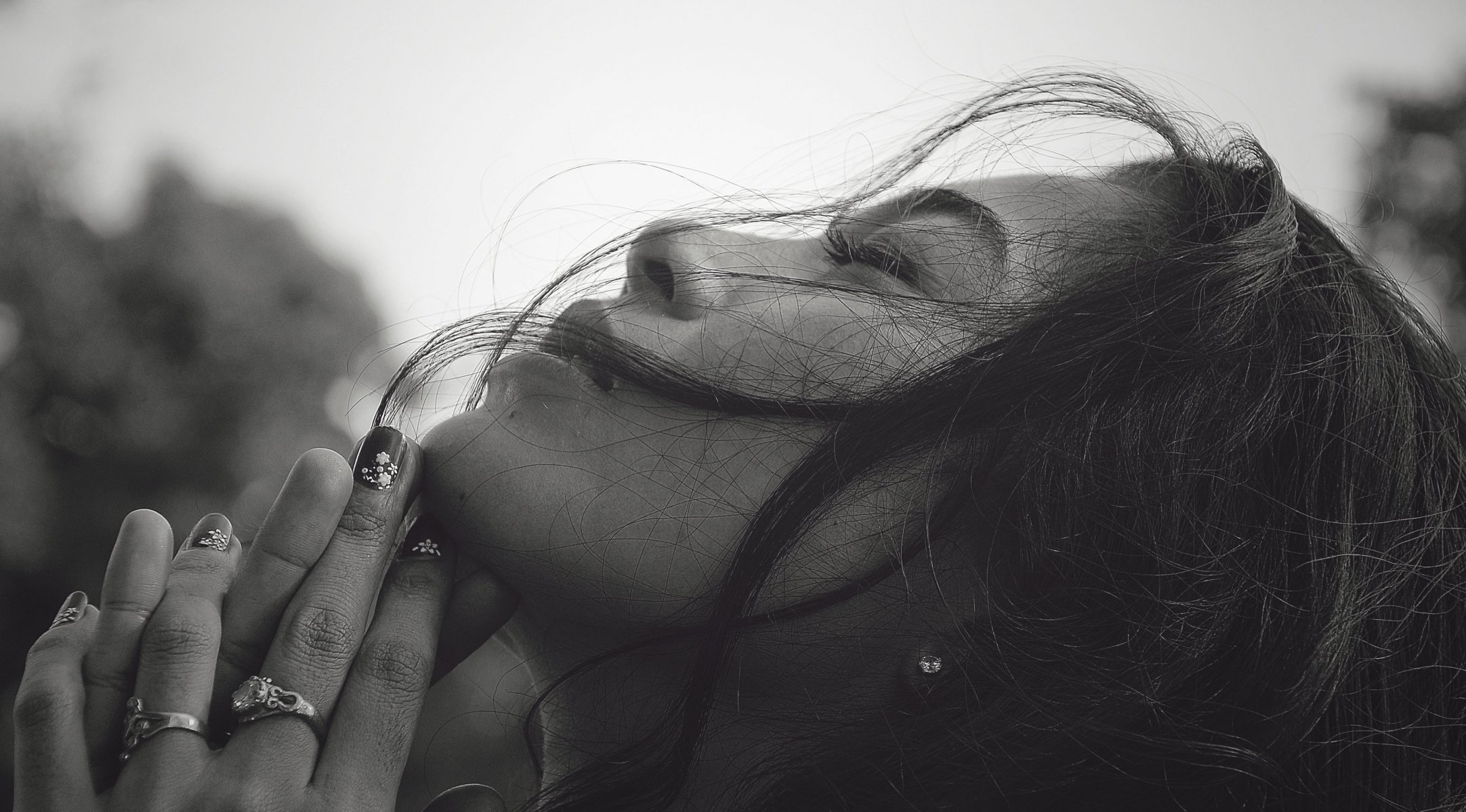 fille noir et blanc visage profil yeux fermés cheveux mains bagues manucure