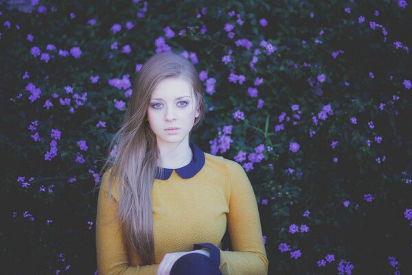 Portrait of a beautiful girl on a background of purple flowers