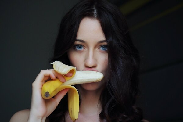 Niebieskooka piękna brunetka zjada banana