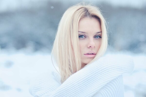 Blonde en pull blanc sur fond de neige