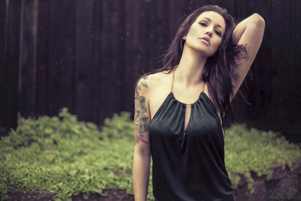 Model in the rain. Girl in tattoos