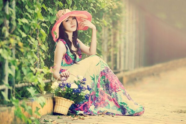 Asiatisches Mädchen mit einem Korb in einem Kleid mit Blumen