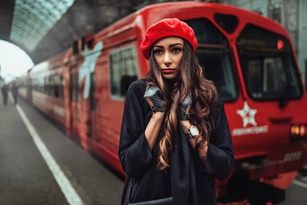 A girl in a coat and beret at the train station