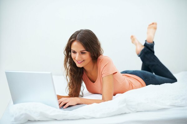 A girl in jeans and a T-shirt at a laptop