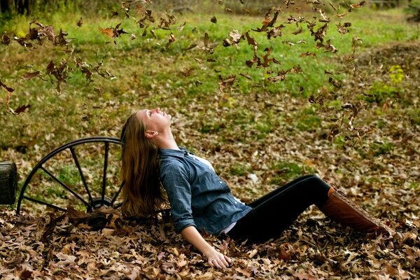 Fille assise sur les feuilles mortes