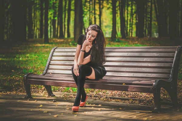 Ragazza in calze e vestito nel parco su una panchina