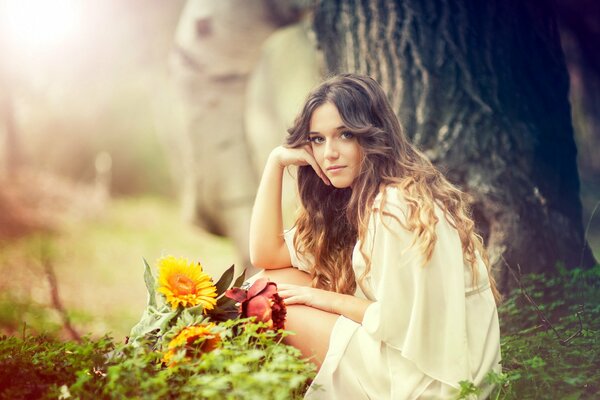 Lorena Bey is sitting in the forest with flowers 