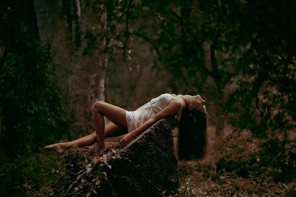 Photo de la jeune fille sur la pierre dans la forêt