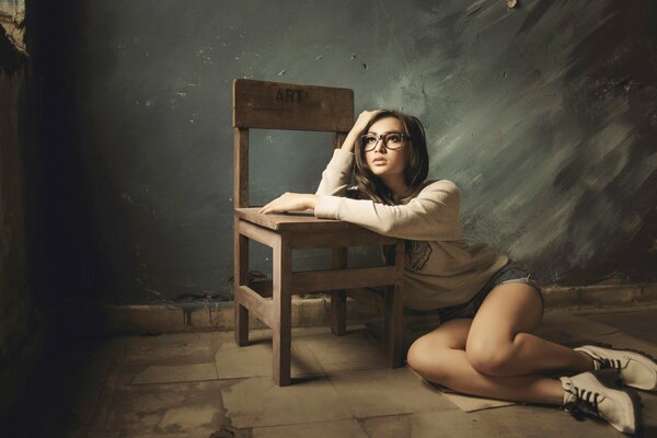 Thoughtful girl with glasses and a chair